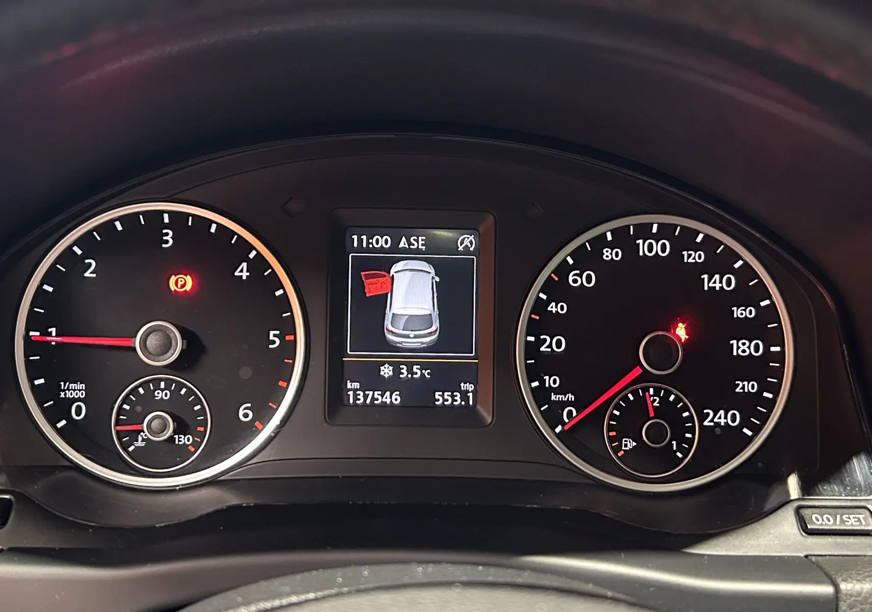 Vue rapprochée du tableau de bord du Volkswagen Tiguan 2015 affichant compte-tours, vitesse et écran central avec porte ouverte.