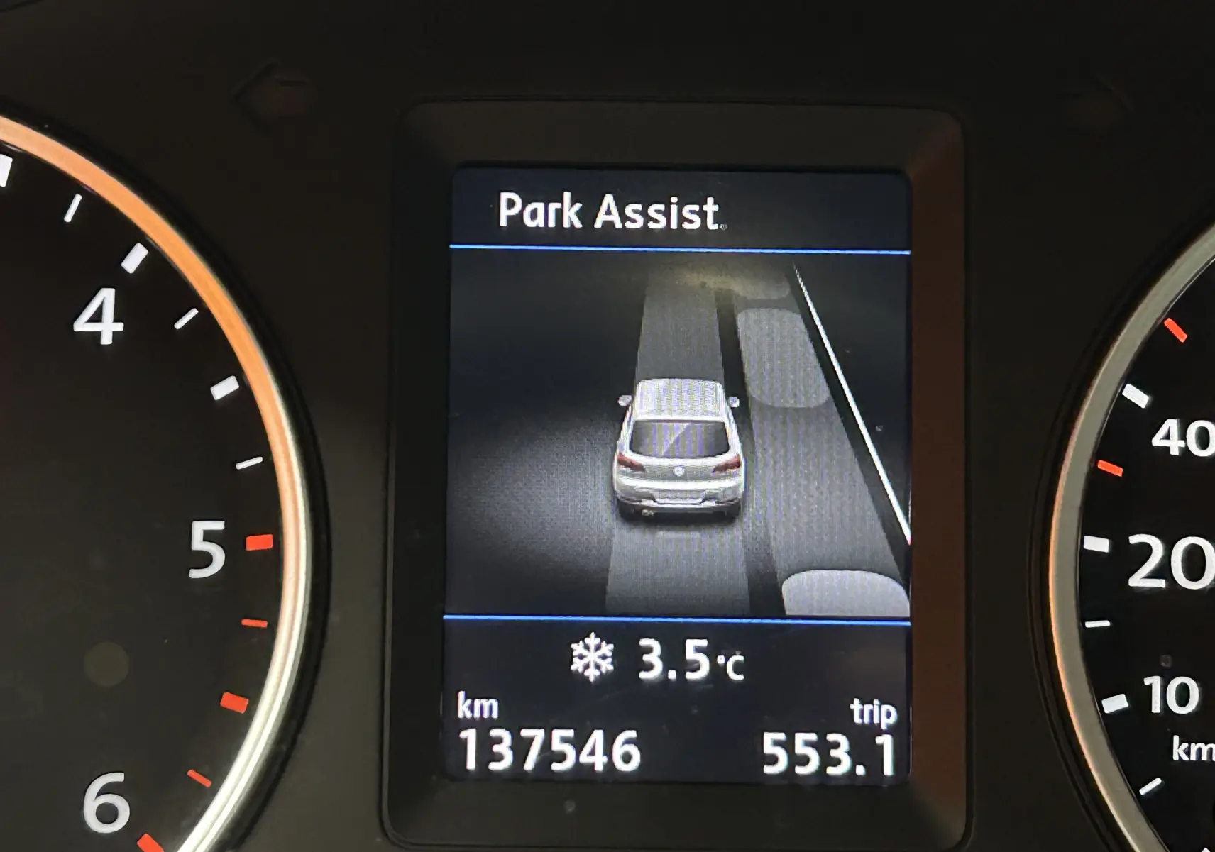 Affichage du tableau de bord du Volkswagen Tiguan 2015 montrant l'assistance au stationnement et le compteur kilométrique.