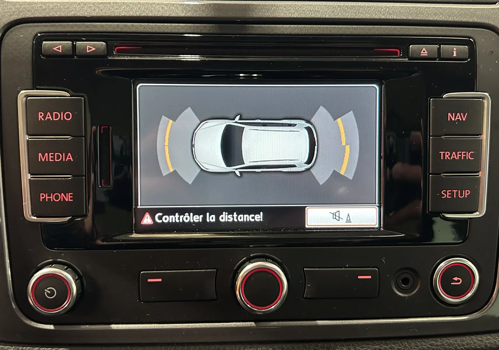 Vue rapprochée de l'écran central du Volkswagen Tiguan 2015 affichant l'alerte de contrôle de distance au stationnement.