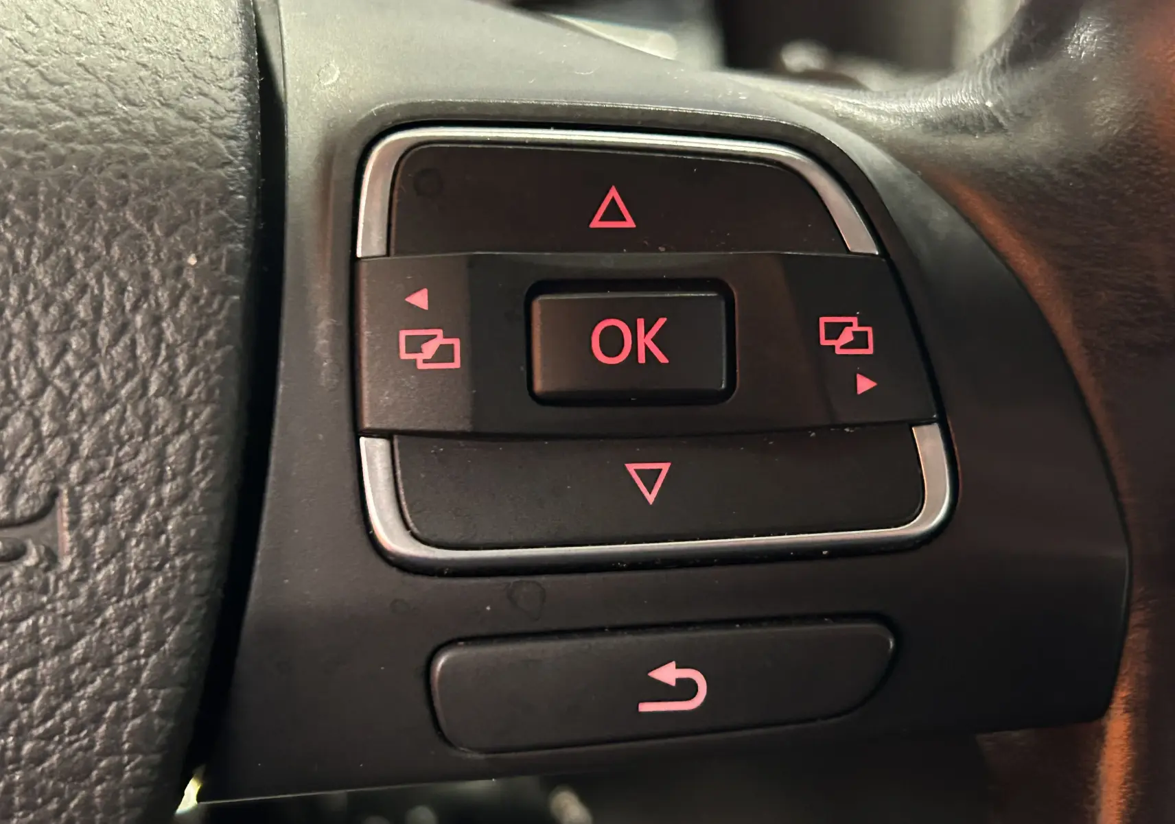 Gros plan sur les commandes de direction au volant du Volkswagen Tiguan 2015 noir métal avec boutons rétroéclairés rouges.