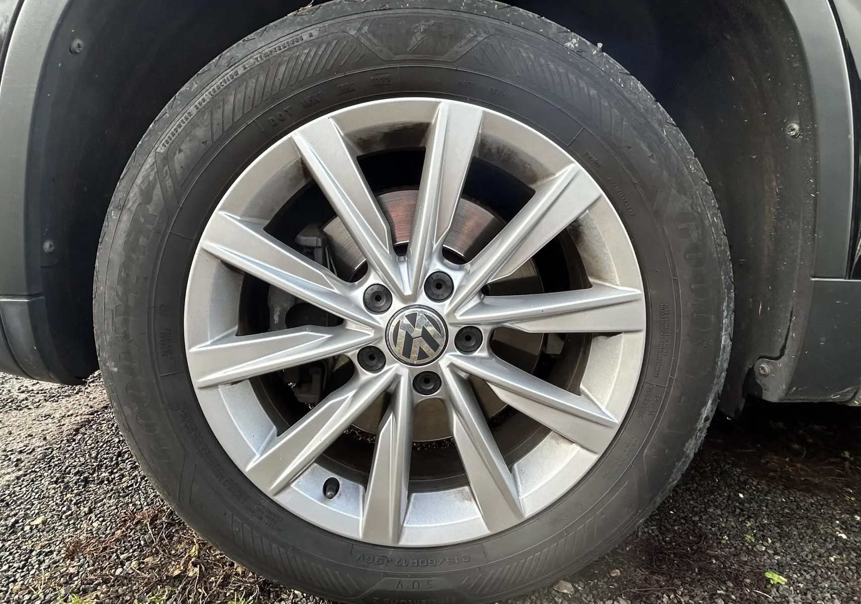 Gros plan sur la roue avant gauche du Volkswagen Tiguan noir métal, mettant en valeur la jante alliage à dix rayons.