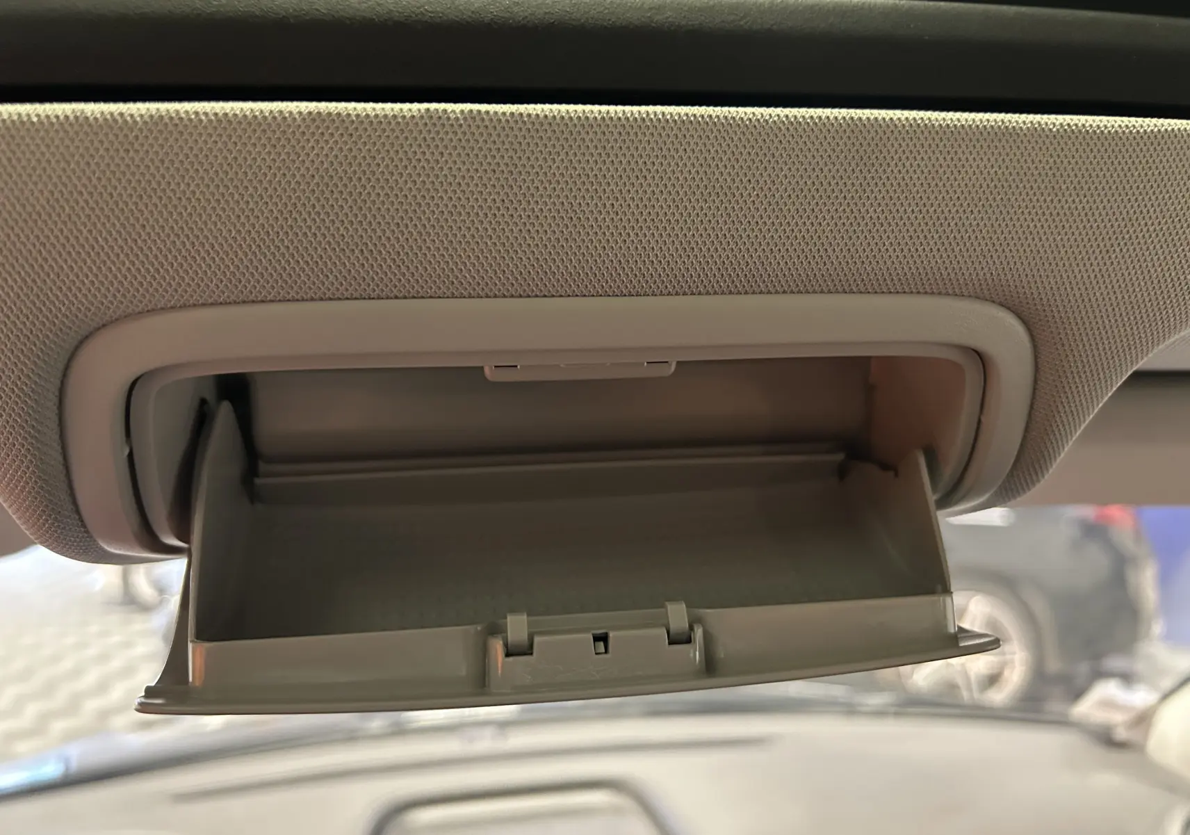 Boîte à lunettes ouverte sous le toit ouvrant du Volkswagen Tiguan noir métal, vue intérieure avant.