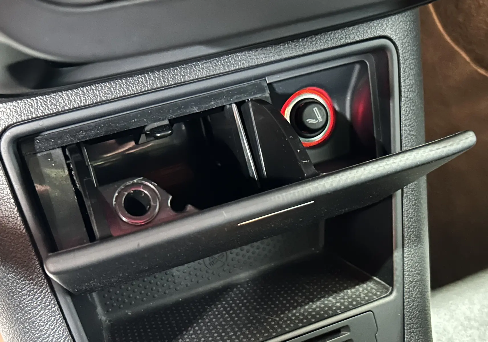 Gros plan sur le cendrier ouvert et l'allume-cigare avec bouton de siège chauffant dans un Volkswagen Tiguan noir 2015.