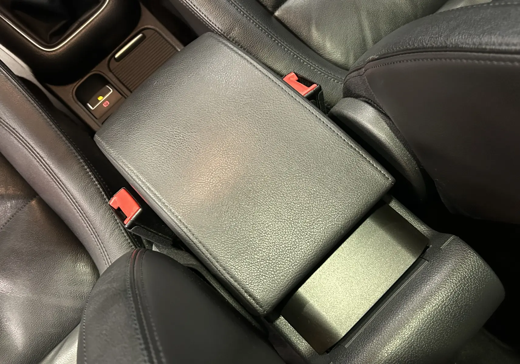 Gros plan sur l'accoudoir central en cuir noir et les sièges avant du Volkswagen Tiguan 2.0 TDI 140 Carat de 2015.