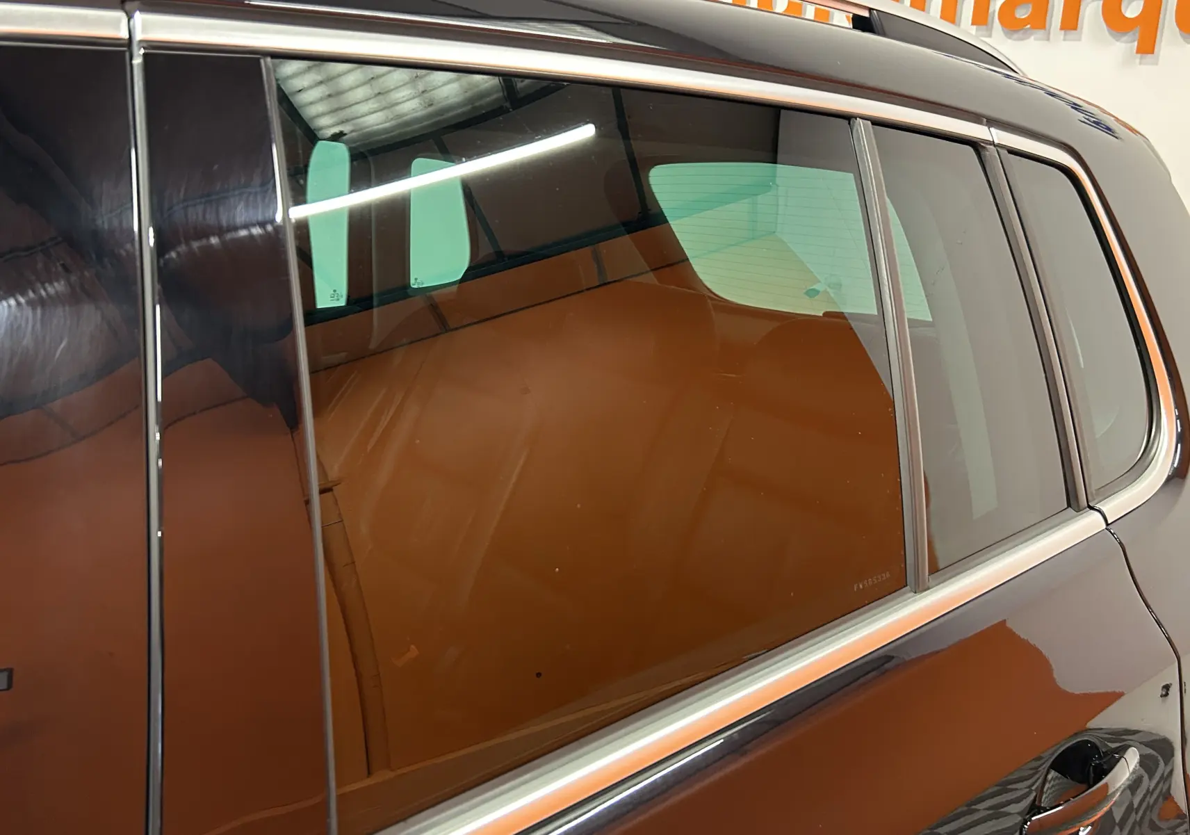 Vue latérale droite sur la porte arrière d'un Volkswagen Tiguan noir métal avec vitres teintées et intérieur cuir visible.