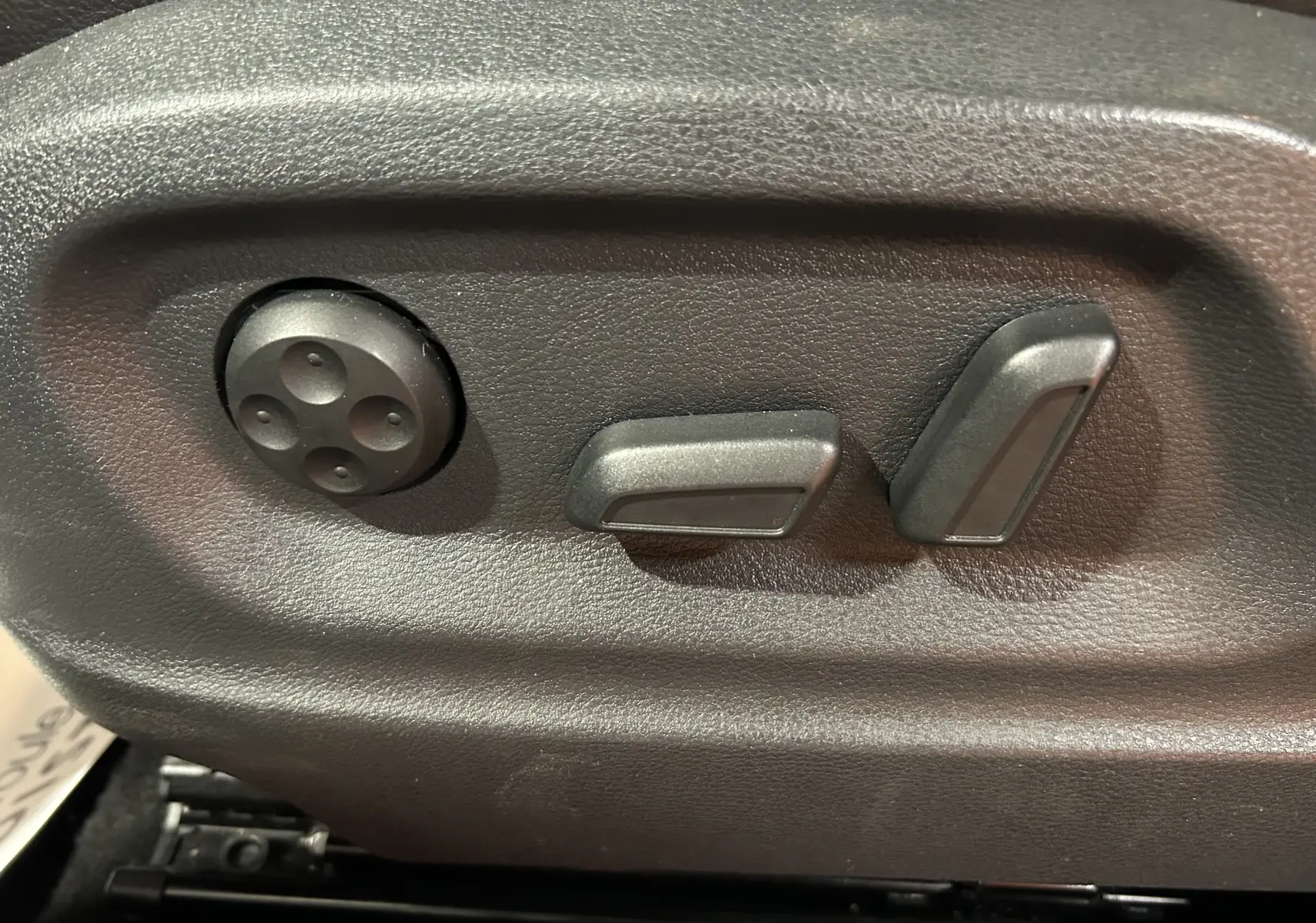 Commandes de réglage électrique des sièges en cuir dans un Volkswagen Tiguan noir métal de 2015.