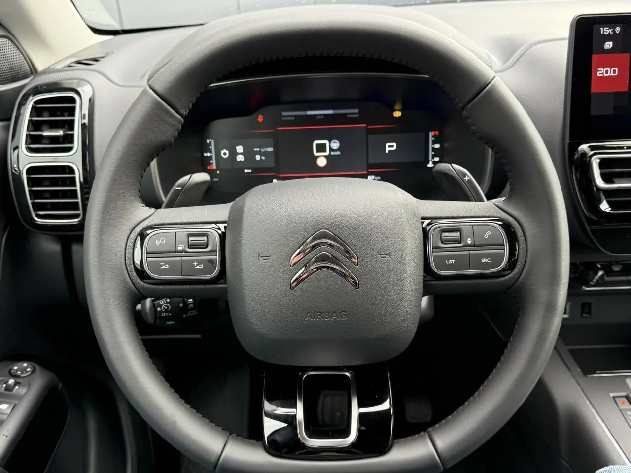 Vue rapprochée du volant noir du Citroën C5 Aircross 2025 avec commandes intégrées et tableau de bord numérique.