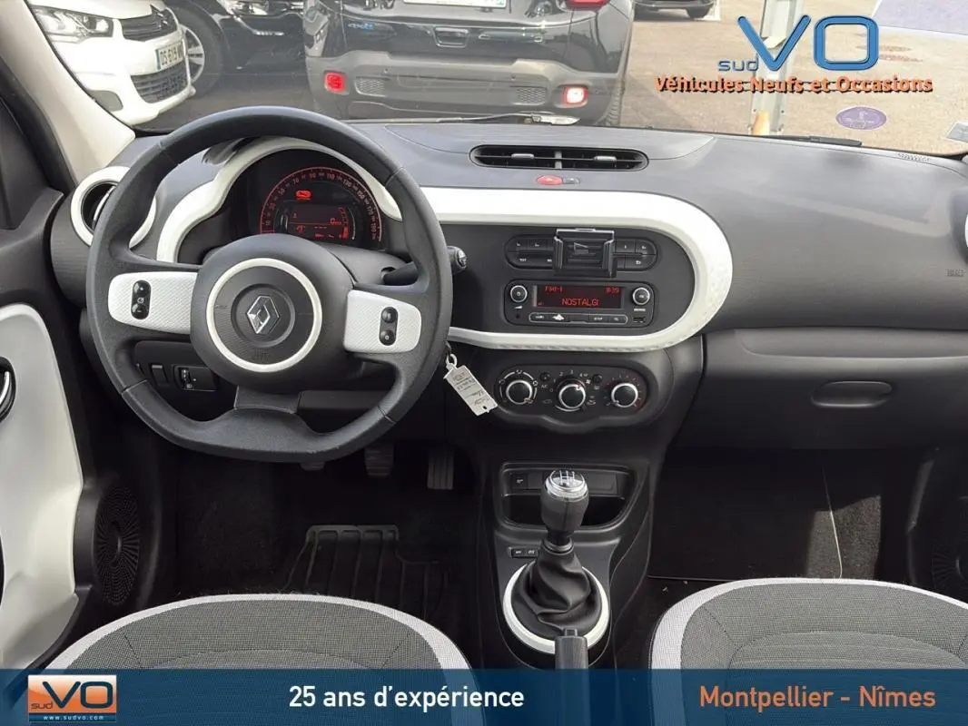 Vue intérieure avant de la Renault Twingo III bleu clair, tableau de bord et volant avec boîte manuelle visibles.