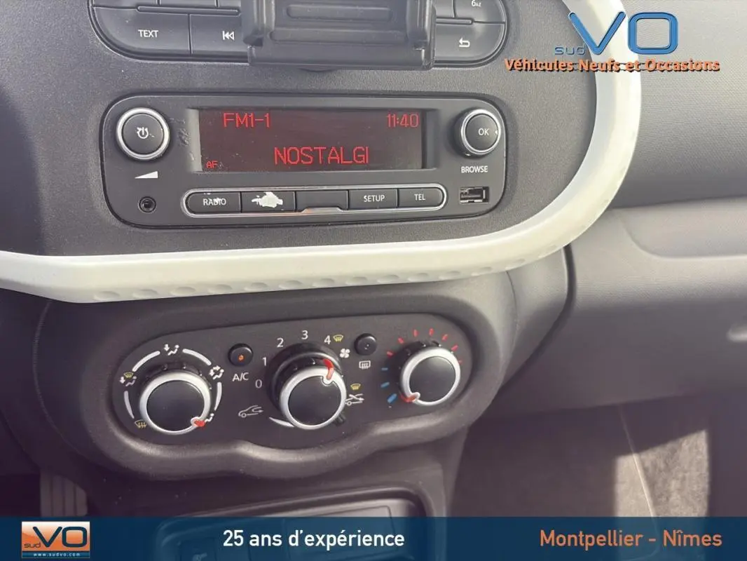 Détail du tableau de bord de la Renault Twingo III bleu clair, avec commandes de climatisation manuelle et radio affichant "NOSTALGI".