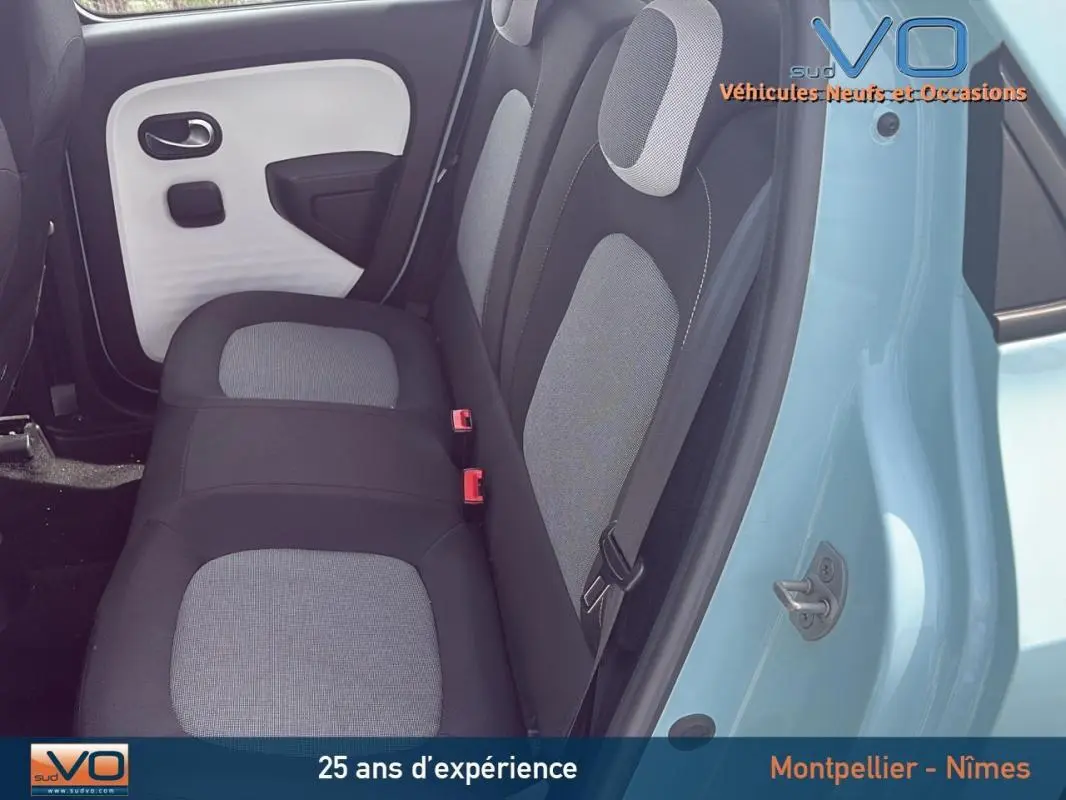 Vue intérieure côté gauche des sièges arrière gris et noir d'une Renault Twingo III bleu clair avec porte ouverte.