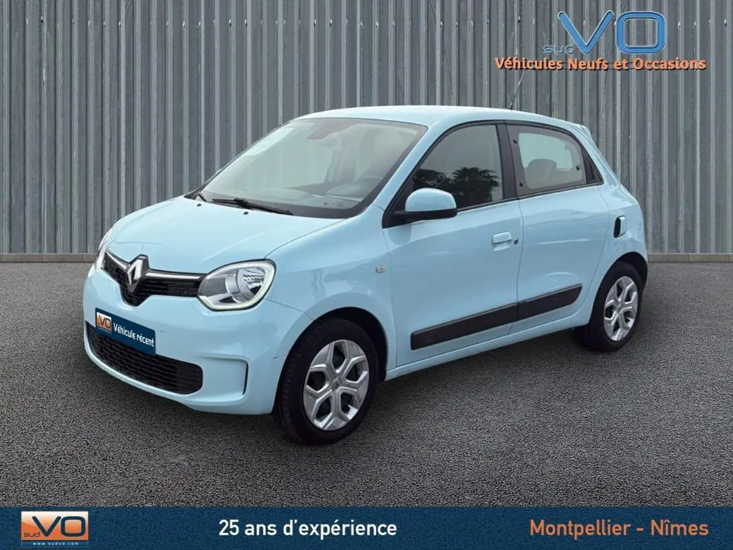 Renault Twingo III bleu clair vue 3/4 avant droit, compacte et moderne sur fond neutre urbain.