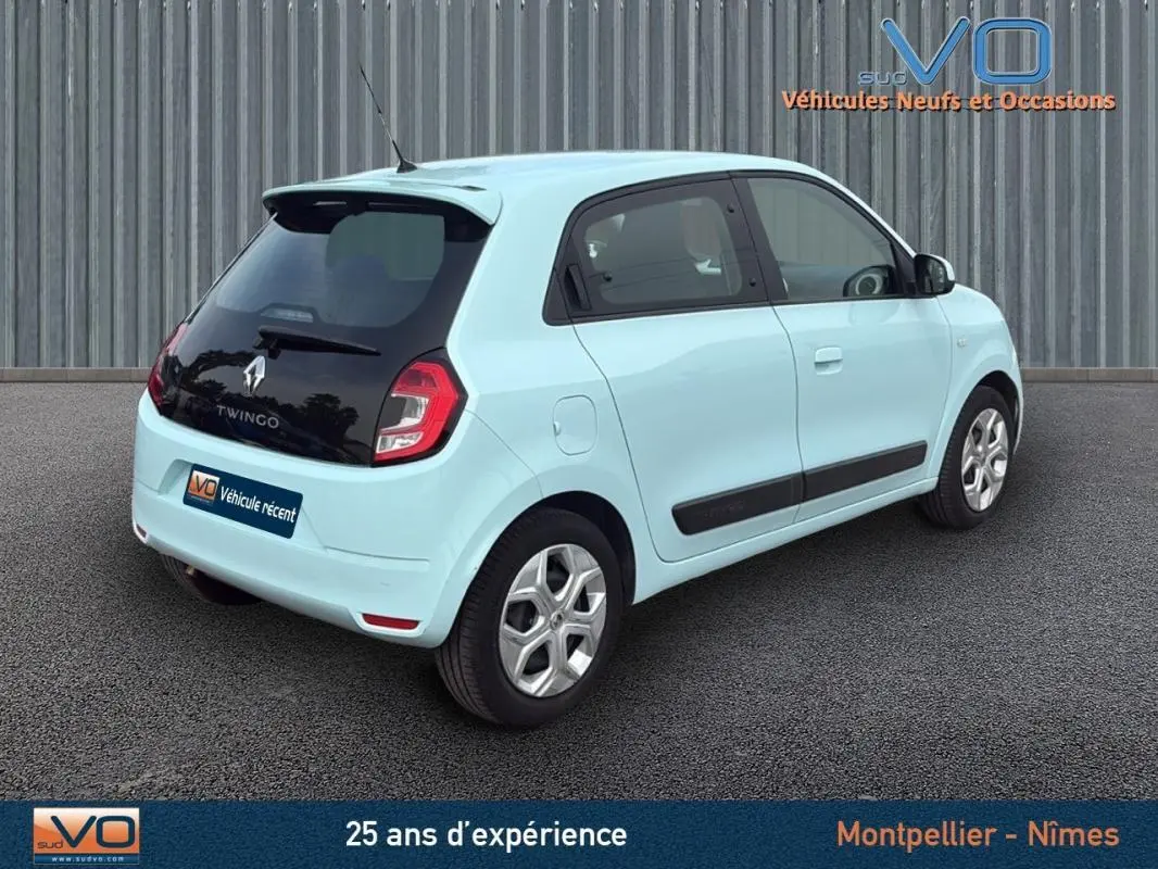 Renault Twingo III bleu clair vue 3/4 arrière droit, avec toit noir et jantes argentées, stationnée sur sol gris.