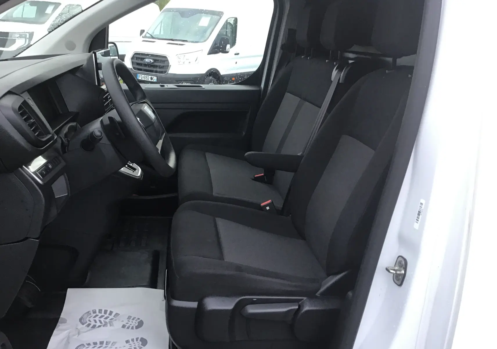 Vue intérieure côté conducteur du FIAT Scudo Fourgon blanc 2024, montrant les sièges avant et le tableau de bord sobre.