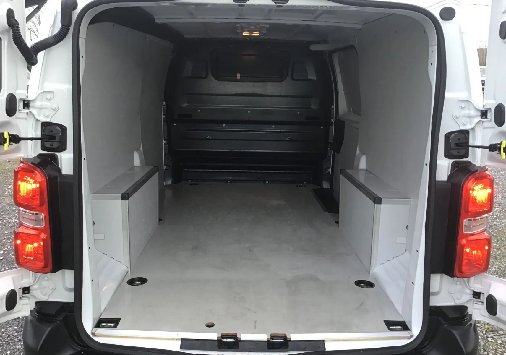 Vue arrière du fourgon blanc FIAT Scudo XL 2024, espace de chargement vide avec parois et plancher protégés.