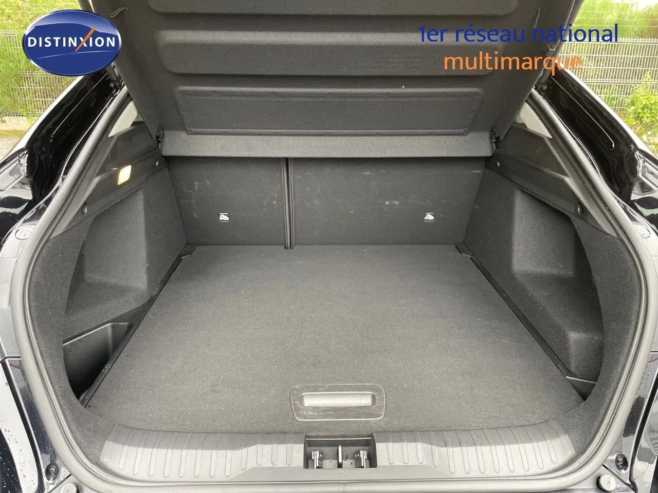 Coffre ouvert vu de l'arrière d'un Renault Arkana noir 2023, espace de chargement spacieux et propre.