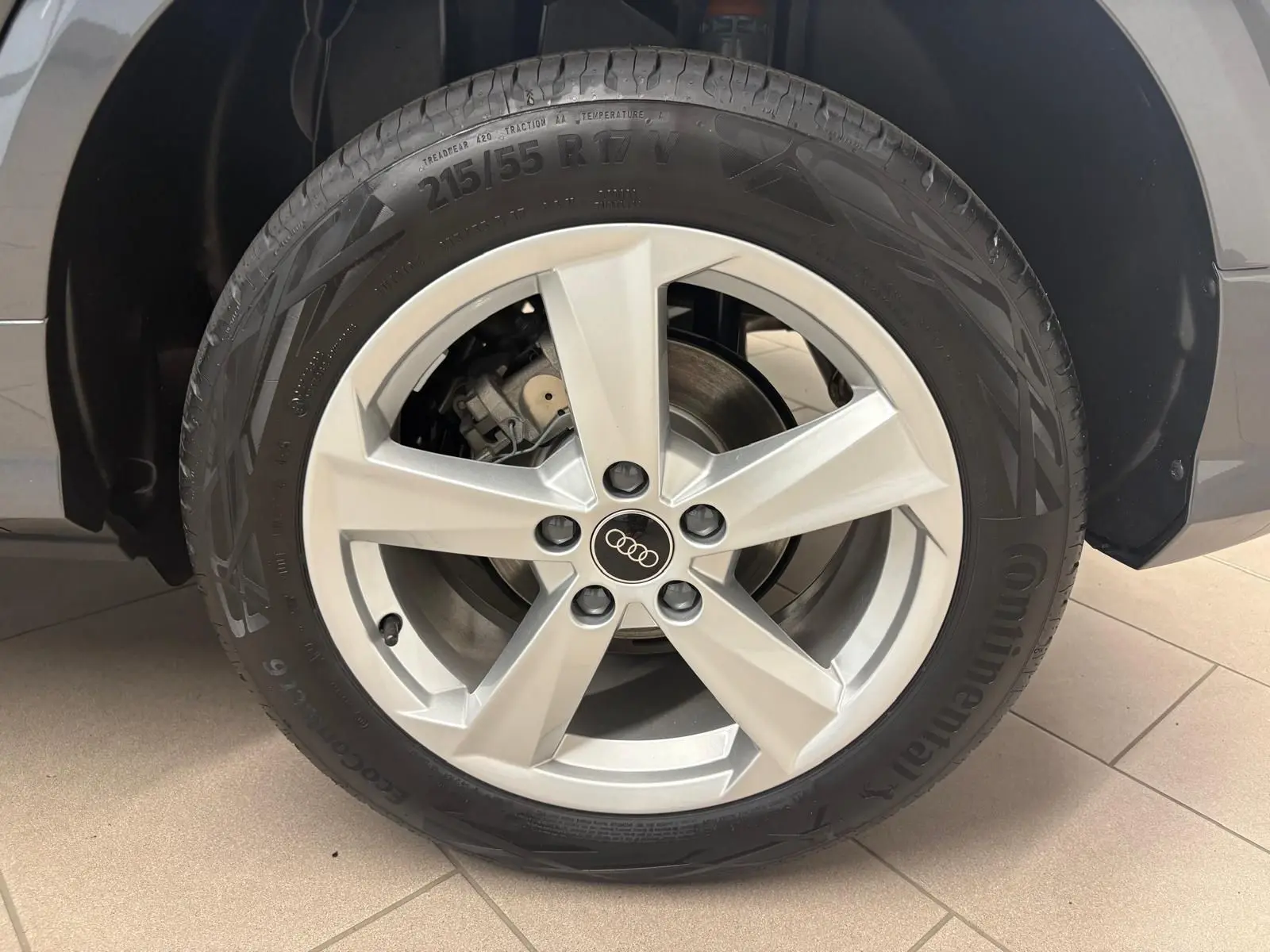 Gros plan sur la roue avant droite d’un Audi Q2 gris Daytona, mettant en valeur la jante alliage 5 branches et le pneu Continental.