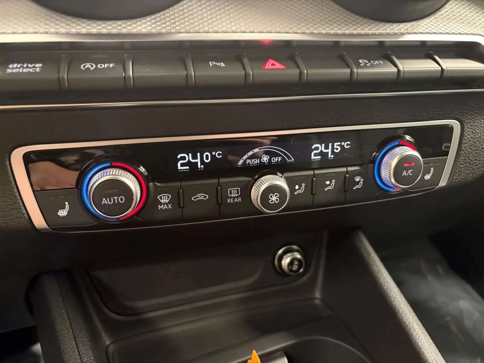 Gros plan sur la console de climatisation automatique de l'Audi Q2 35 TFSI 150 S Line avec réglages numériques et boutons rétroéclairés.