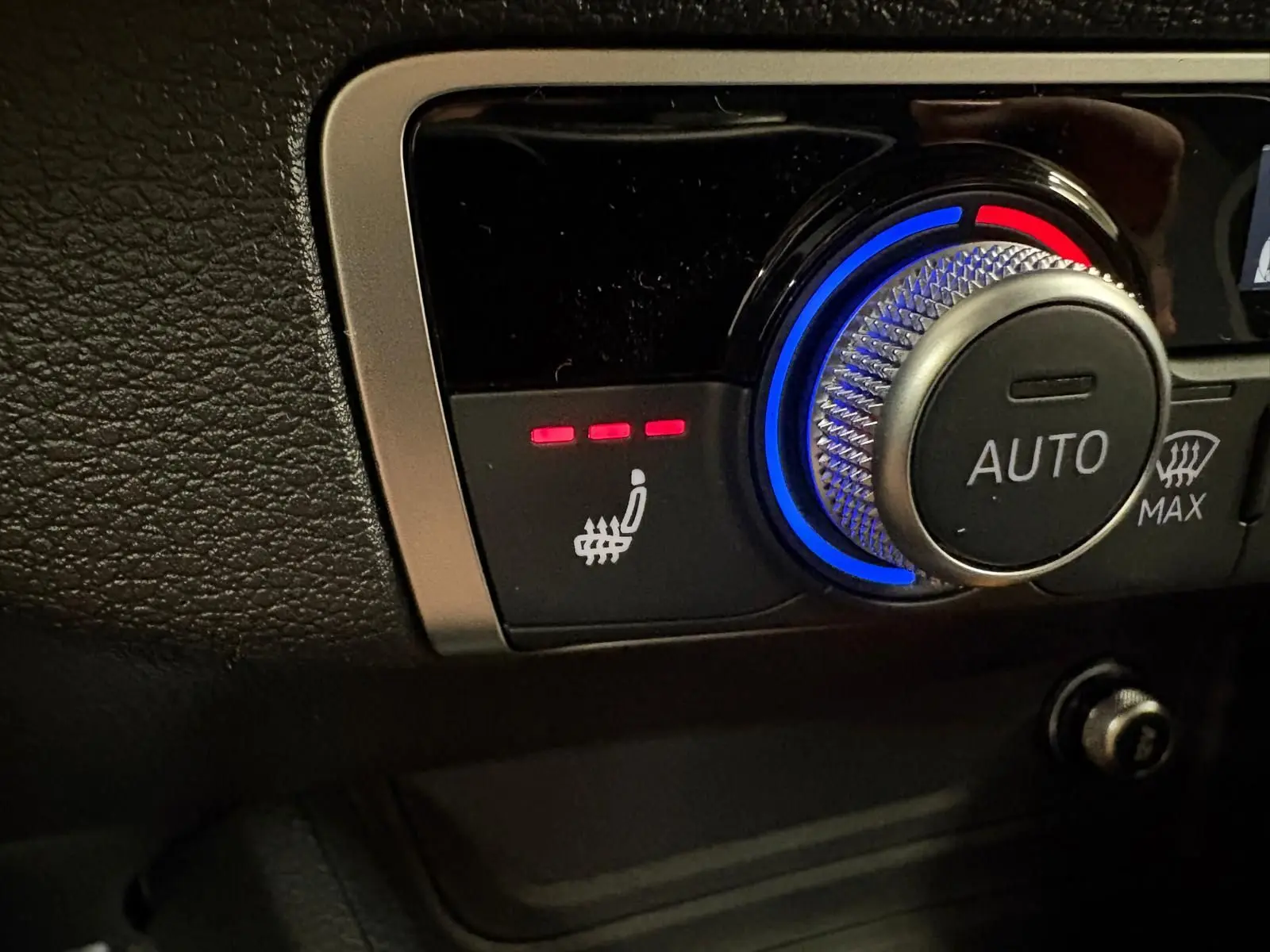 Gros plan sur la commande de siège chauffant et réglage automatique de la climatisation dans l'Audi Q2 Gris Daytona.