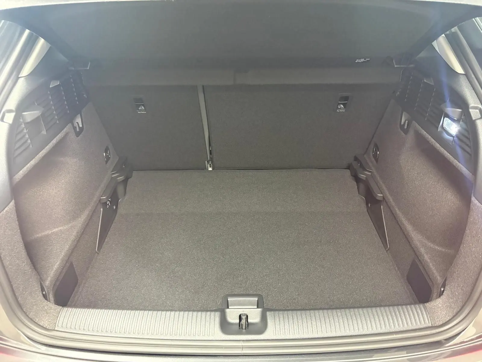 Coffre ouvert de l'Audi Q2 35 TFSI S Line 2026 en gris Daytona, montrant un espace de chargement propre et bien éclairé.