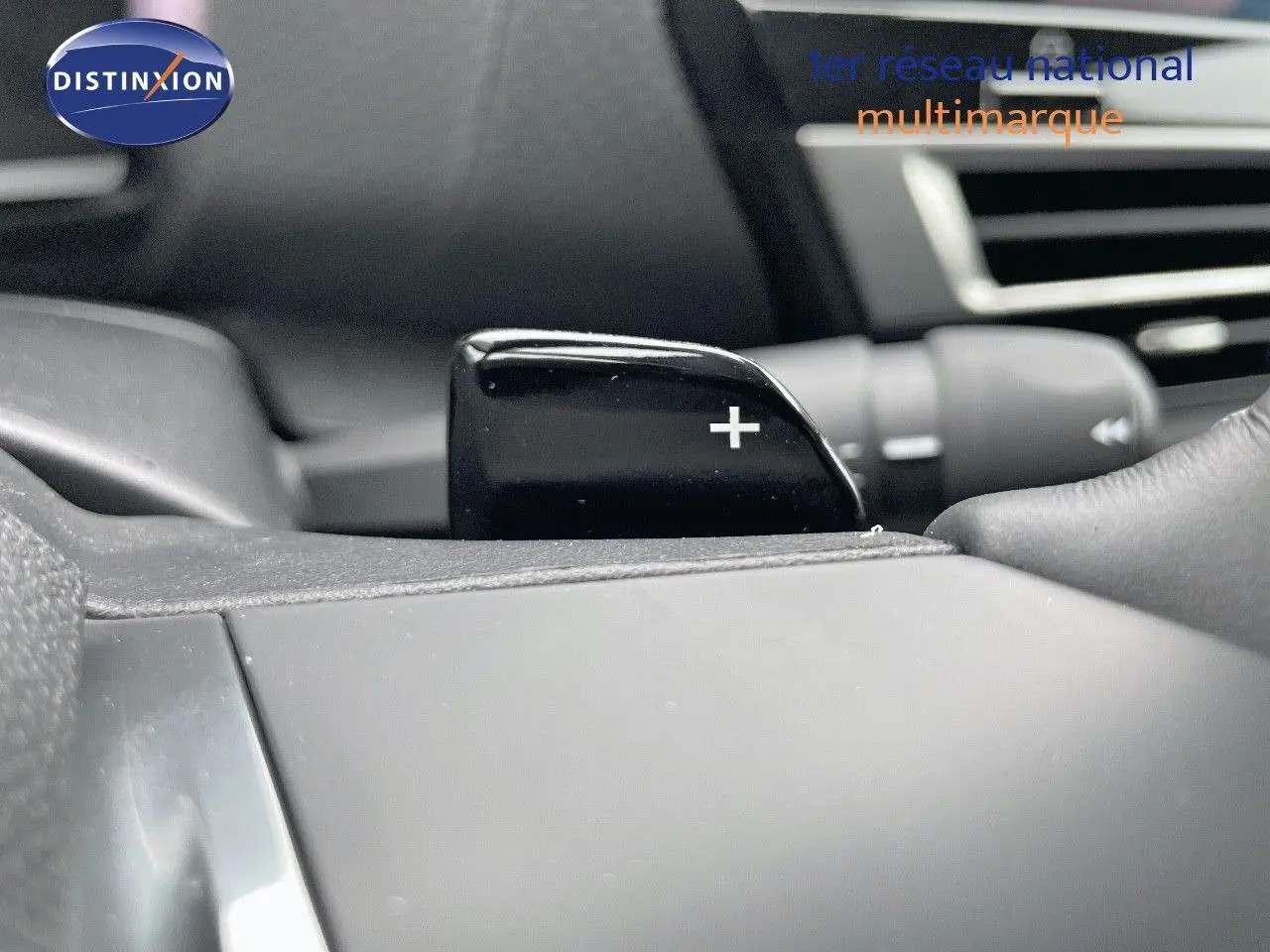 Gros plan sur la palette de changement de vitesse "+" côté droit du volant d'une Citroën C4 blanche métal 2024.