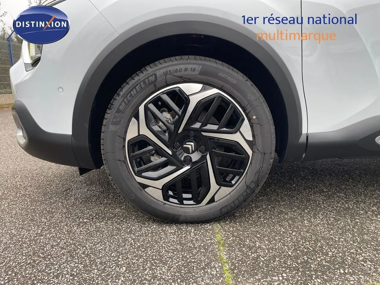 Gros plan sur la roue avant gauche d'une Citroën C4 blanche métal 2024 avec jante alliage bicolore distinctive.
