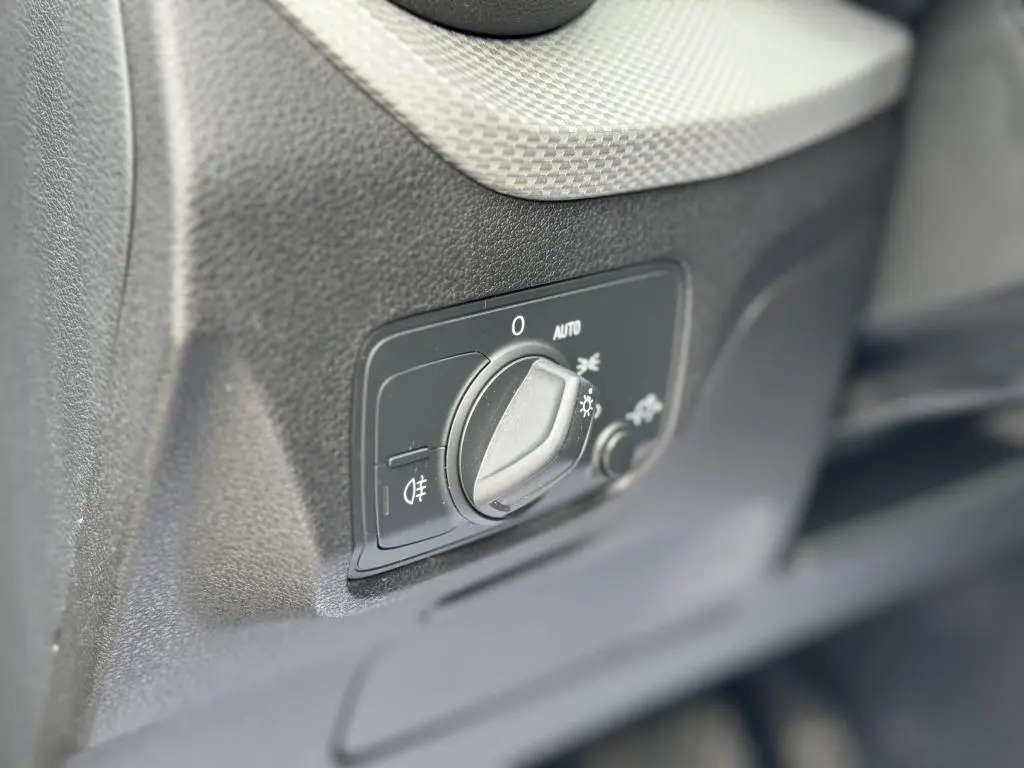 Gros plan sur le bouton de commande des phares dans l'habitacle noir de l'Audi Q2 2022 Design Diesel.