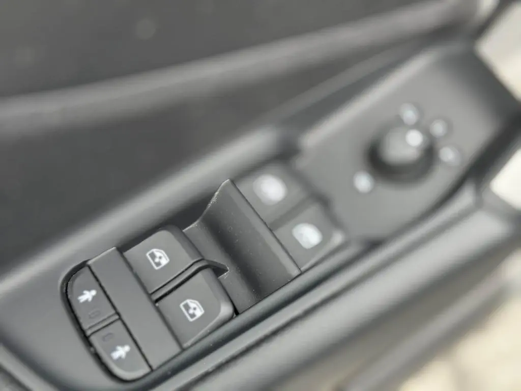 Gros plan sur les commandes des vitres électriques et rétroviseurs côté gauche d'un Audi Q2 noir 2022.