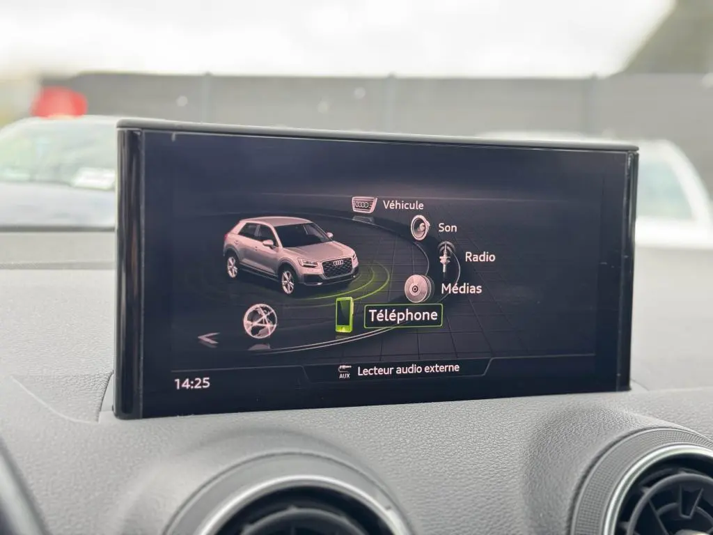 Écran central de l'Audi Q2 affichant le menu multimédia avec une miniature du SUV gris en vue 3/4 avant.