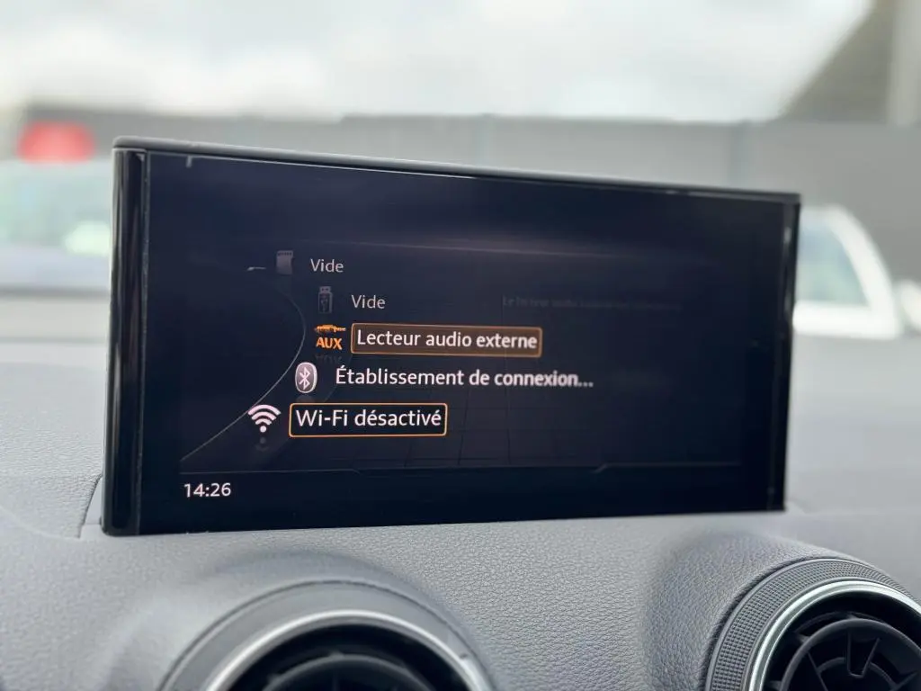 Écran central de l'Audi Q2 noir 2022 affichant les options audio et Wi-Fi désactivé, entouré de la console grise.