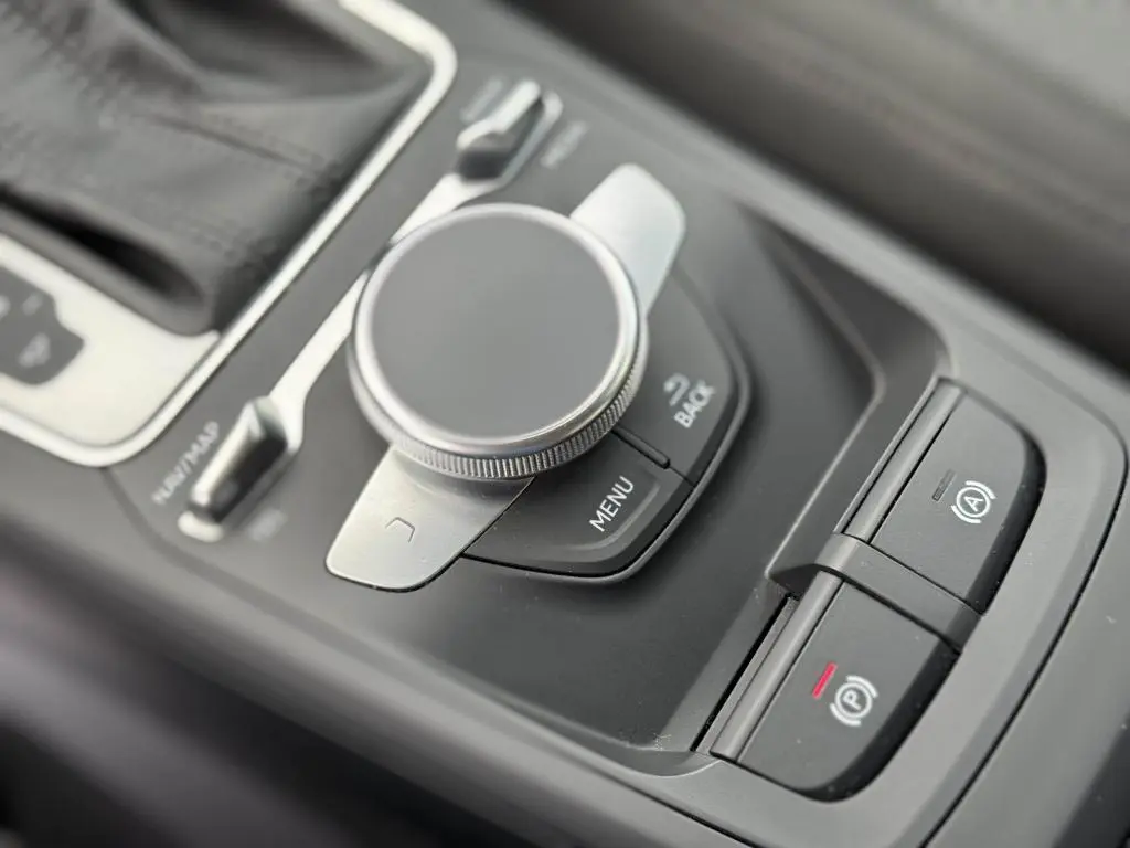 Gros plan sur la molette de commande MMI et les boutons de frein à main électrique dans l'intérieur noir de l'Audi Q2.