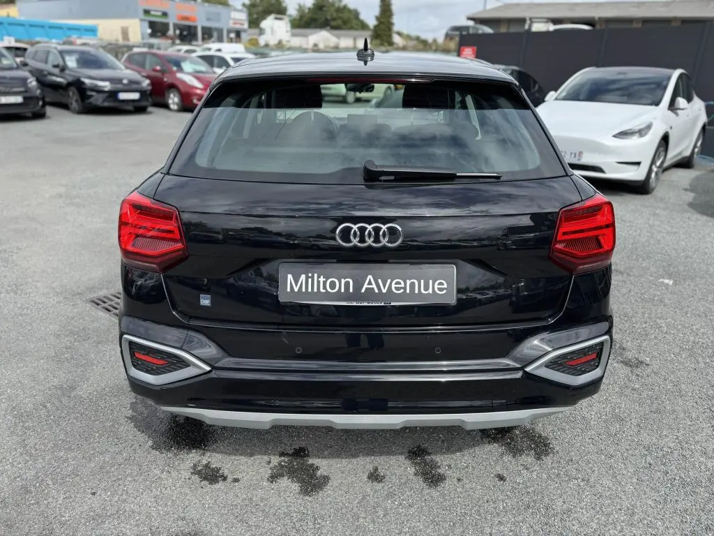 Vue arrière d'un Audi Q2 noir avec feux LED et logo Audi visible sur un parking.