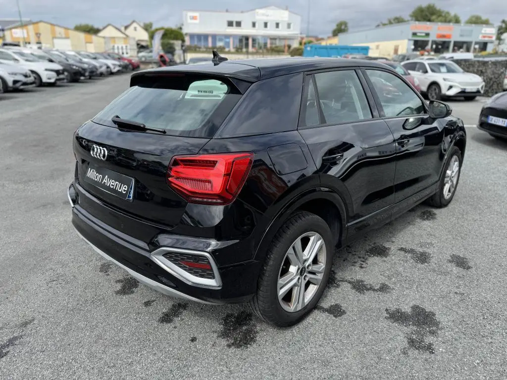 Audi Q2 noire vue en 3/4 arrière droit, avec feux arrière LED et jantes aluminium à 5 branches doubles.