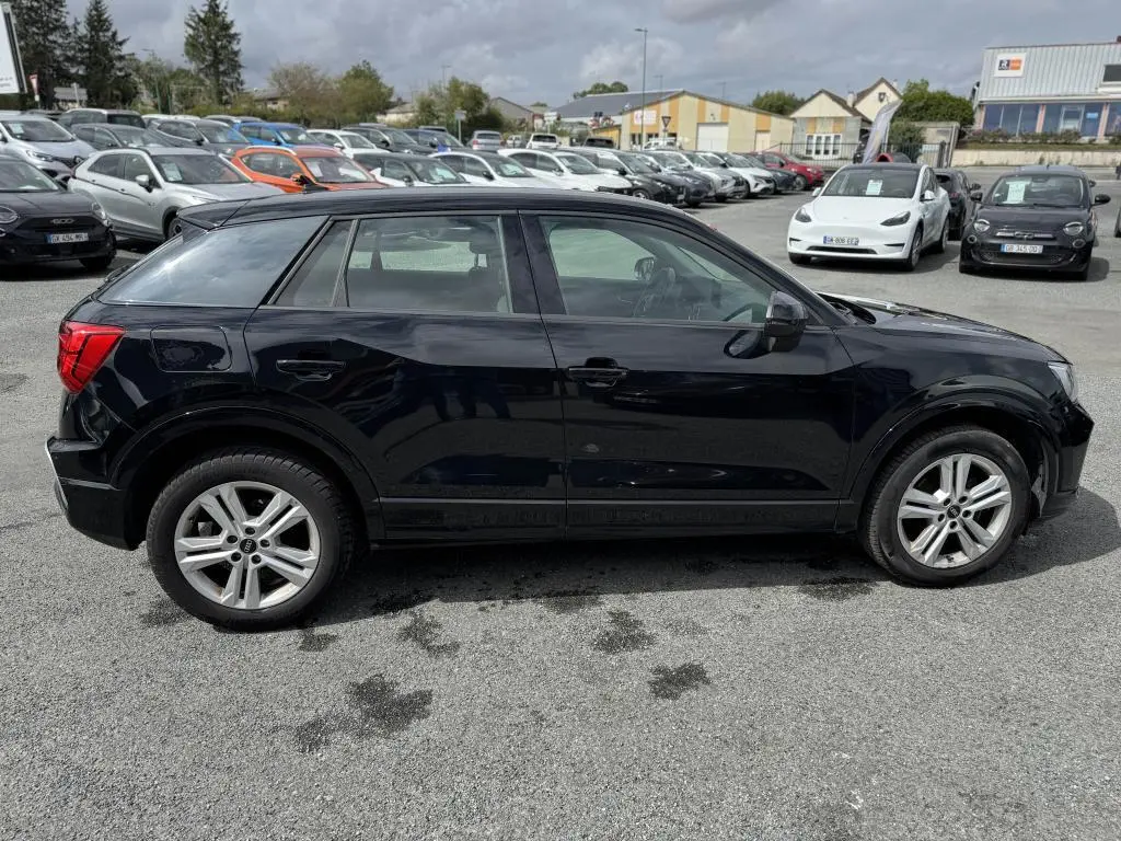 Audi Q2 noire vue de profil côté gauche, avec jantes aluminium 5 branches doubles et vitres teintées.