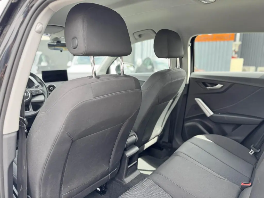 Vue intérieure arrière de l'Audi Q2 2022 noire, montrant les sièges tissu Skript et les appuie-têtes avant et arrière.