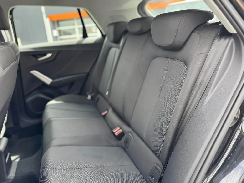 Vue intérieure côté droit des sièges arrière en tissu noir de l'Audi Q2 2022 avec ceintures et appuie-têtes intégrés.