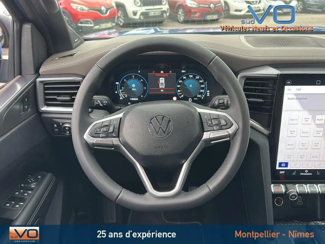 Vue intérieure centrée sur le volant cuir multifonctions du Volkswagen Amarok bleu 2025 avec écran digital et commandes intégrées.