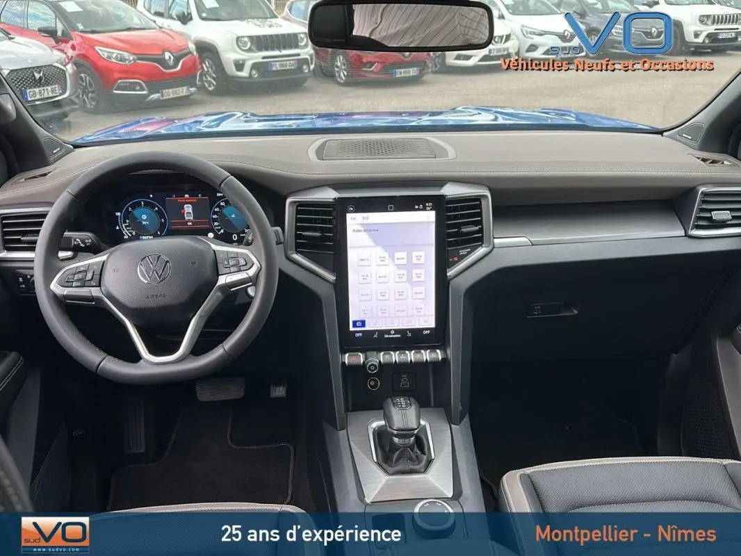 Intérieur du Volkswagen Amarok Simple Cabine 2025 bleu, vue frontale sur le tableau de bord avec écran tactile vertical et volant cuir.