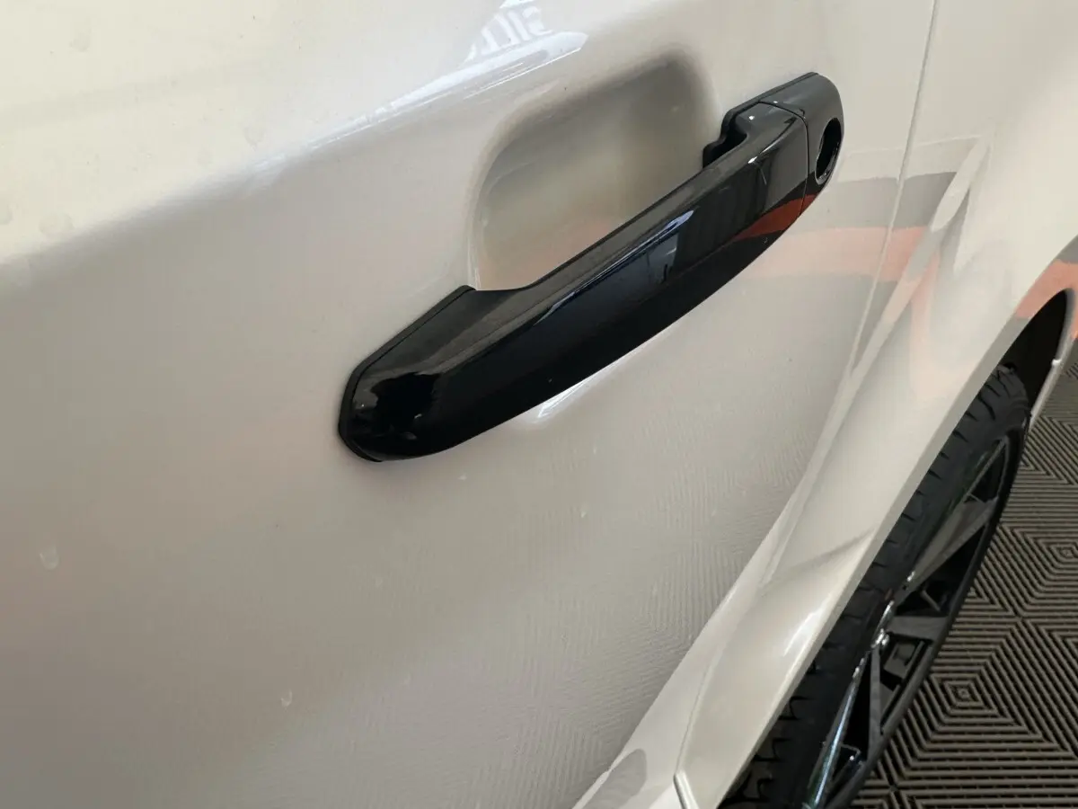 Gros plan sur la poignée de porte noire côté droit d'une Aixam Ambition 0.5 City GTO blanche de 2026.