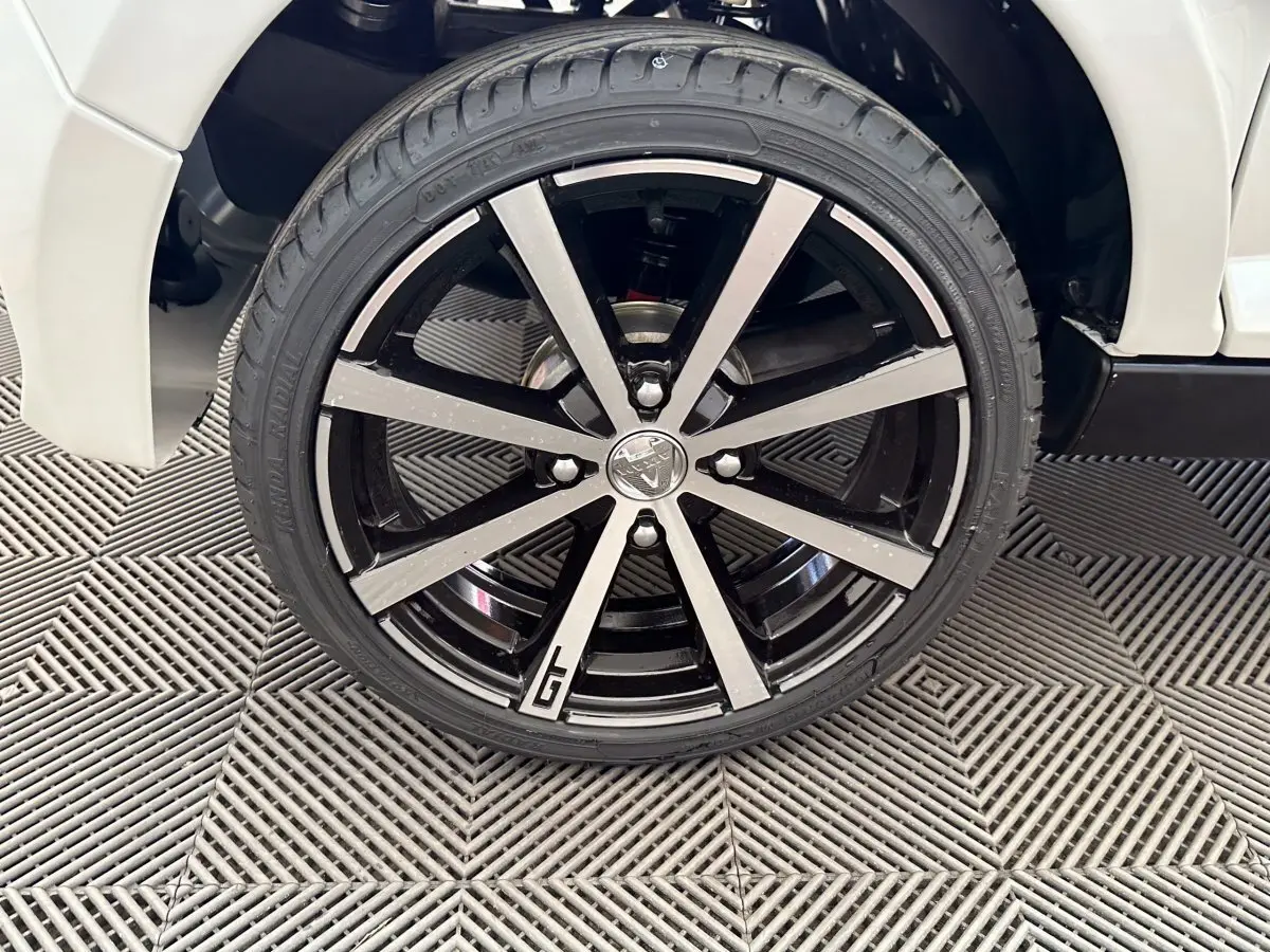 Gros plan sur la roue avant droite de l'AIXAM AMBITION 0.5 CITY GTO blanche, avec jante noire et argentée marquée GTO.