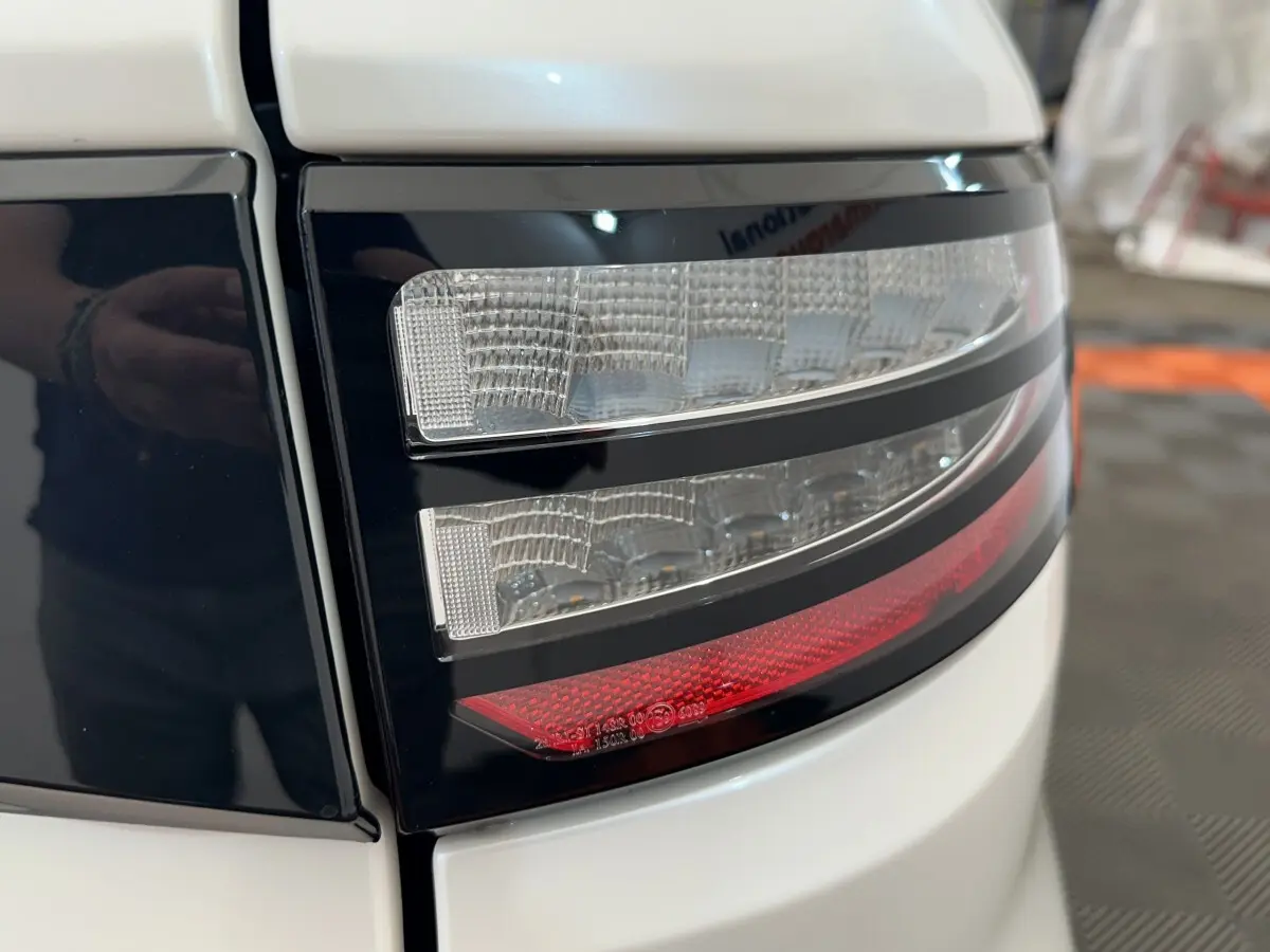 Gros plan sur le feu arrière droit blanc et noir de l'AIXAM AMBITION 0.5 CITY GTO 2026 avec détails lumineux rouges et transparents.