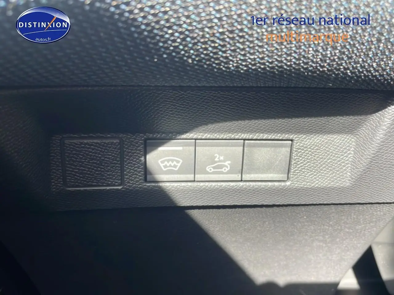 Détail intérieur montrant les boutons d'ouverture du coffre et de dégivrage sur tableau de bord noir du Citroën C5 Aircross blanc.