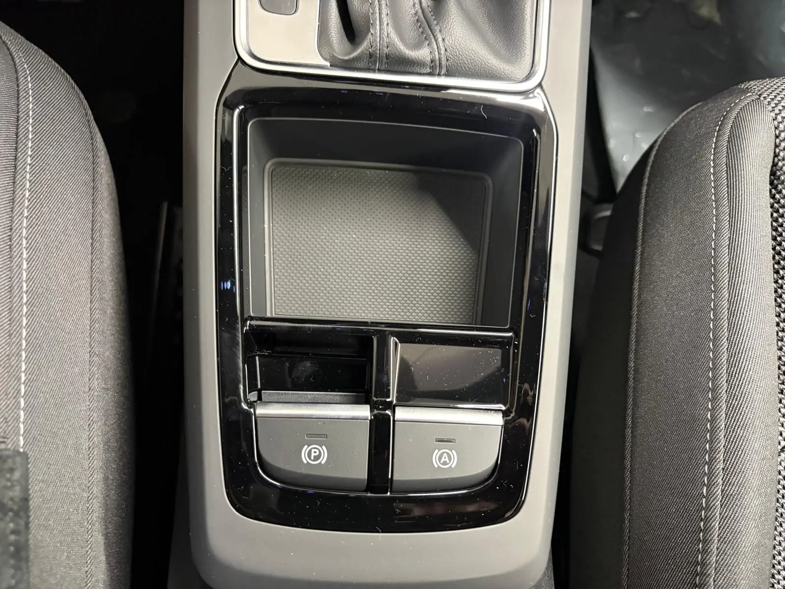 Gros plan sur la console centrale de l'Audi Q2 35 TFSI 150 S Line 2026, avec boutons de frein à main et auto hold.