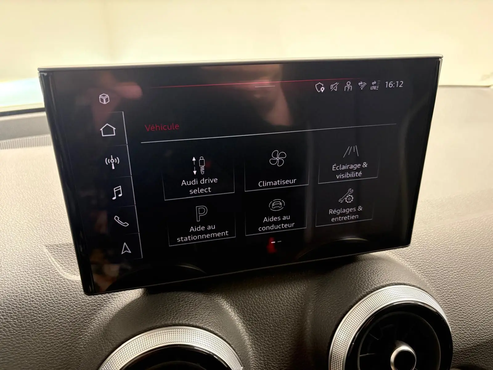 Écran tactile central de l'Audi Q2 35 TFSI 150 S Line 2026, affichant les réglages du véhicule, intérieur noir.