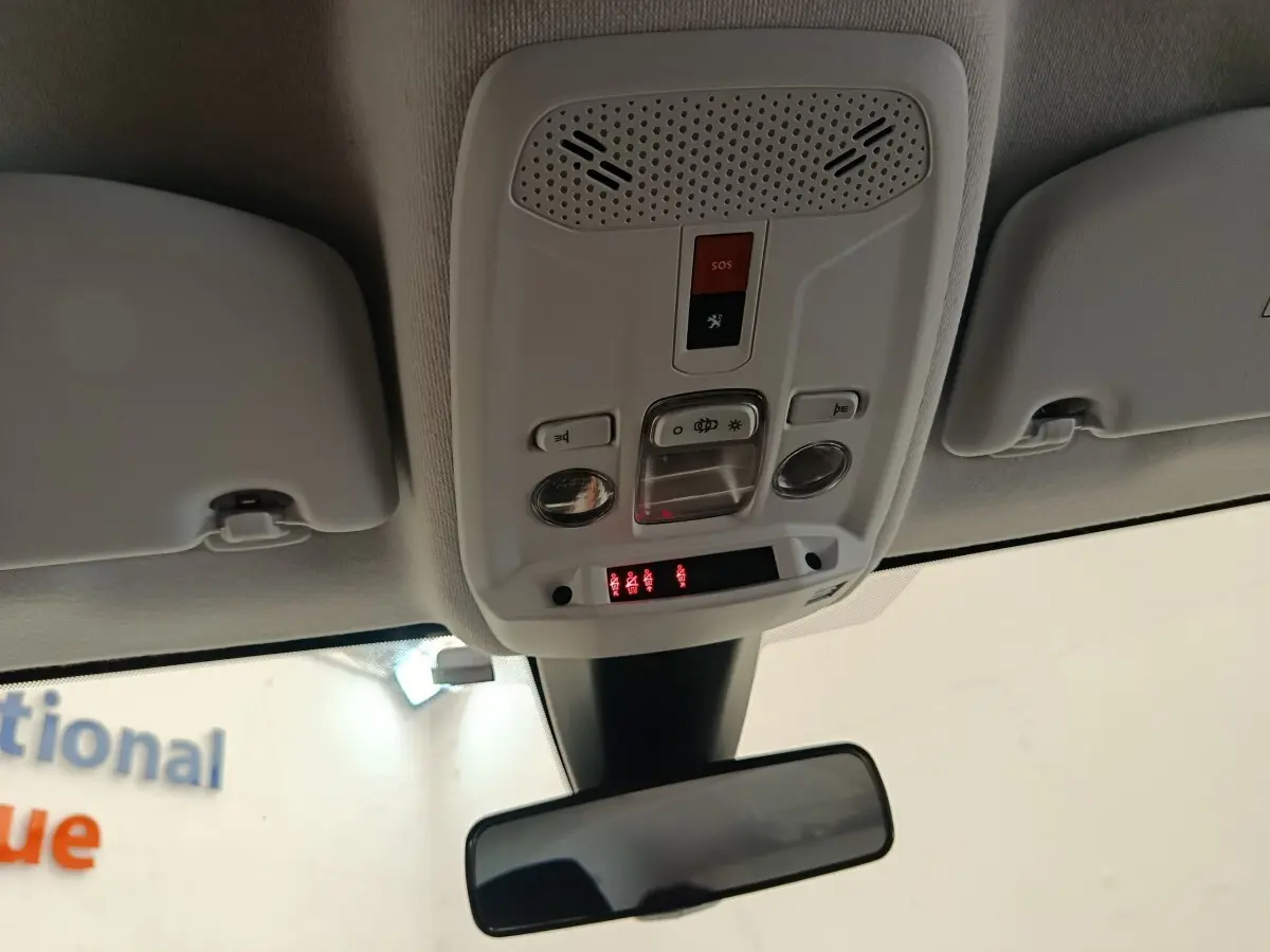 Vue intérieure en plongée du plafonnier blanc avec commandes d’éclairage et bouton SOS dans une Peugeot 208 blanche.