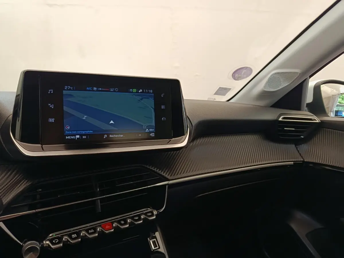 Vue intérieure du tableau de bord de la Peugeot 208 PureTech 75 blanc, avec écran tactile de navigation central.