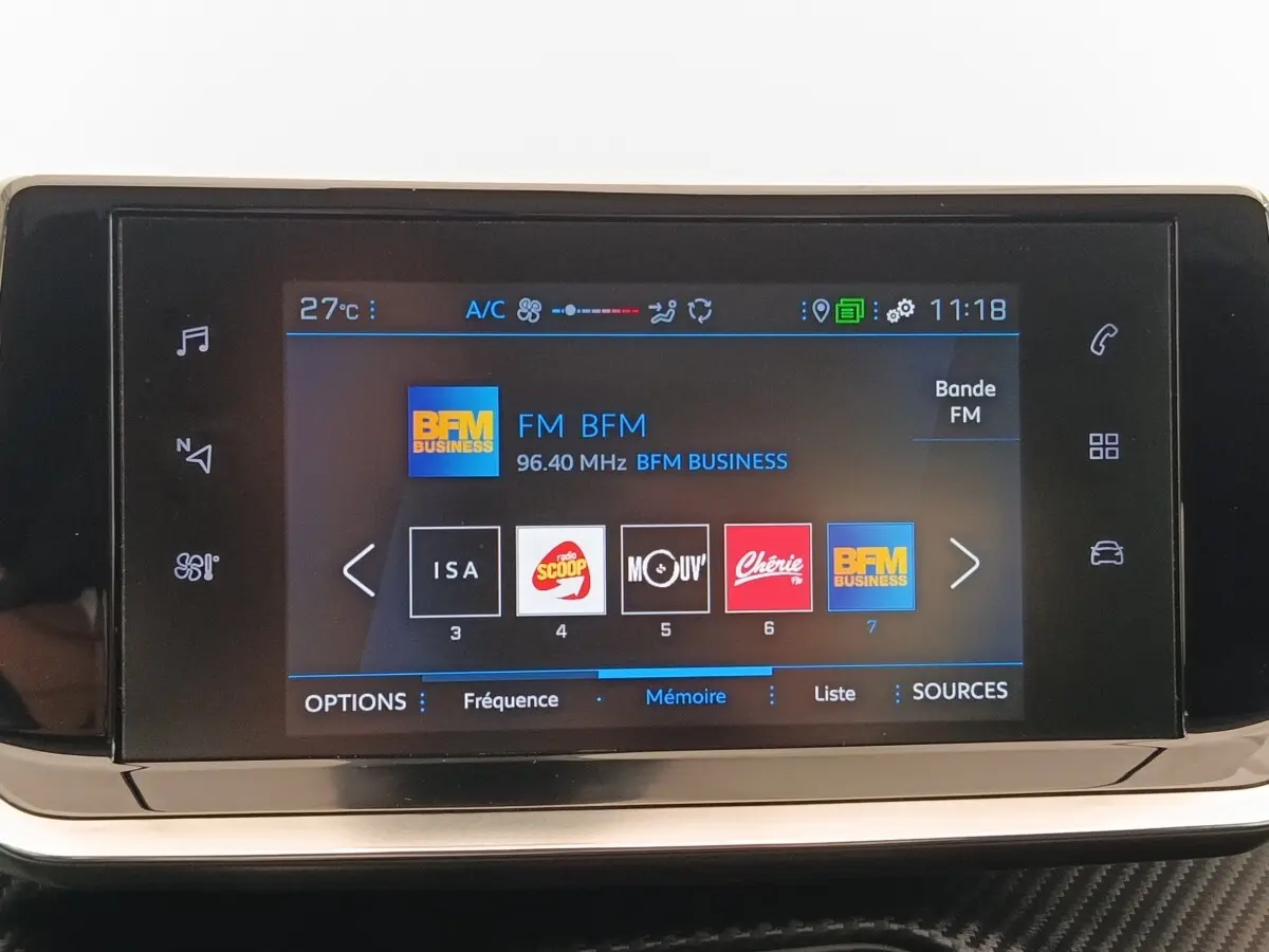 Écran tactile central de la Peugeot 208 blanc affichant les stations radio FM avec interface moderne et icônes colorées.