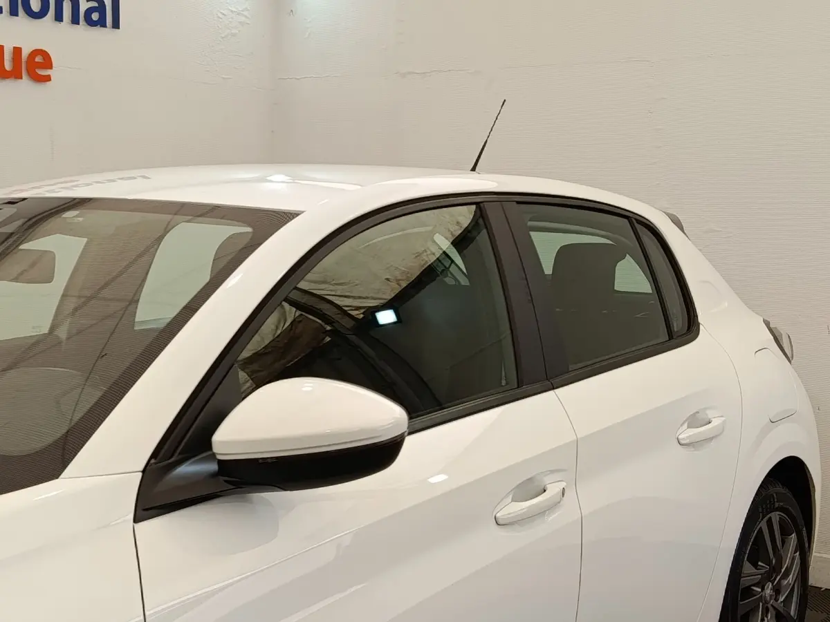 Vue côté gauche d'une Peugeot 208 blanche PureTech 75 S&S Active Business, avec rétroviseur et poignées assortis.