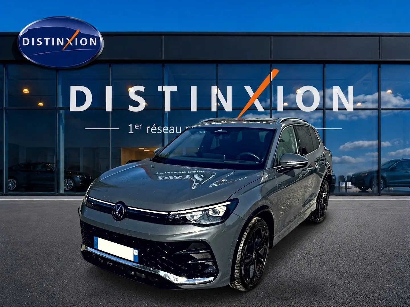 Volkswagen Tiguan 2.0 TDI gris dauphin en 3/4 avant droit, avec jantes noires et calandre R-Line visible.
