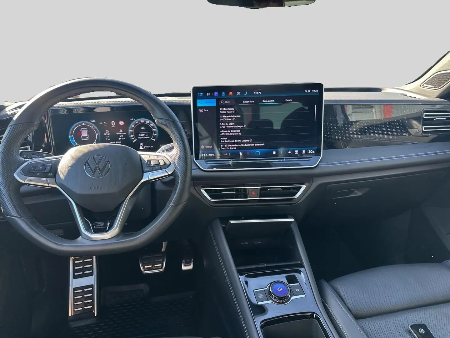 Vue intérieure frontale du Volkswagen Tiguan 2024, tableau de bord noir avec écran tactile central et volant multifonction cuir.