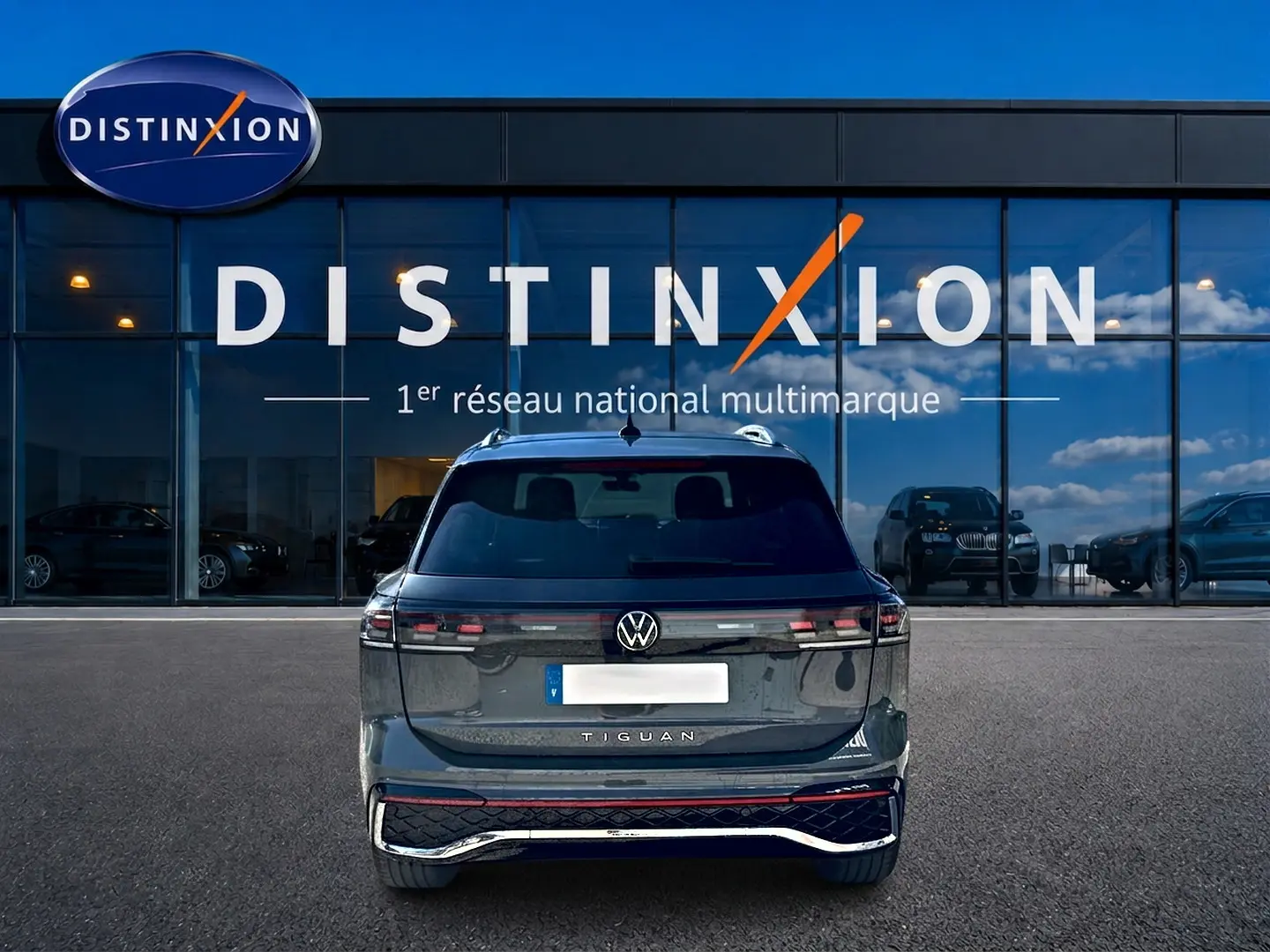 Vue arrière du Volkswagen Tiguan gris dauphin 2024, avec feux LED et logo VW bien visibles devant une vitrine Distinxion.